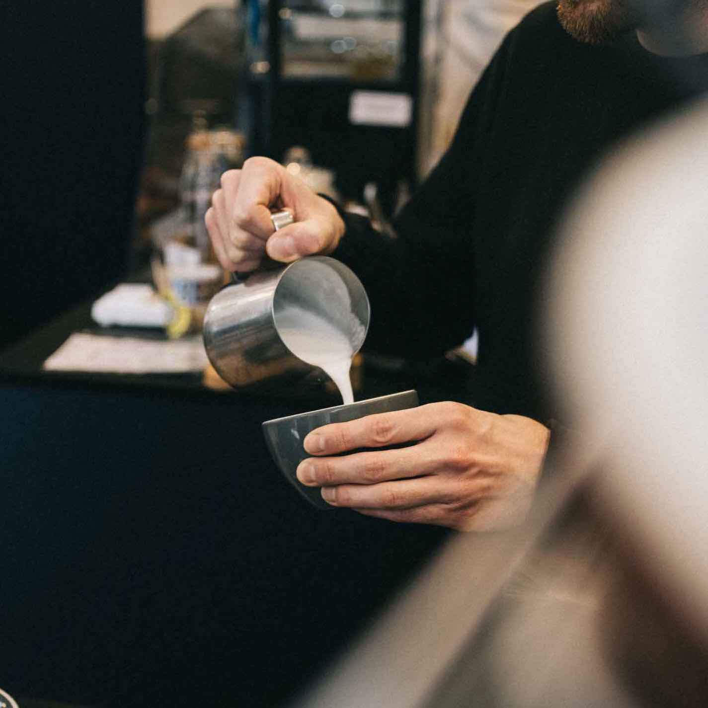 zoom sur une personne versant du lait pour terminer la préparation du chai latte bio de chez awachai