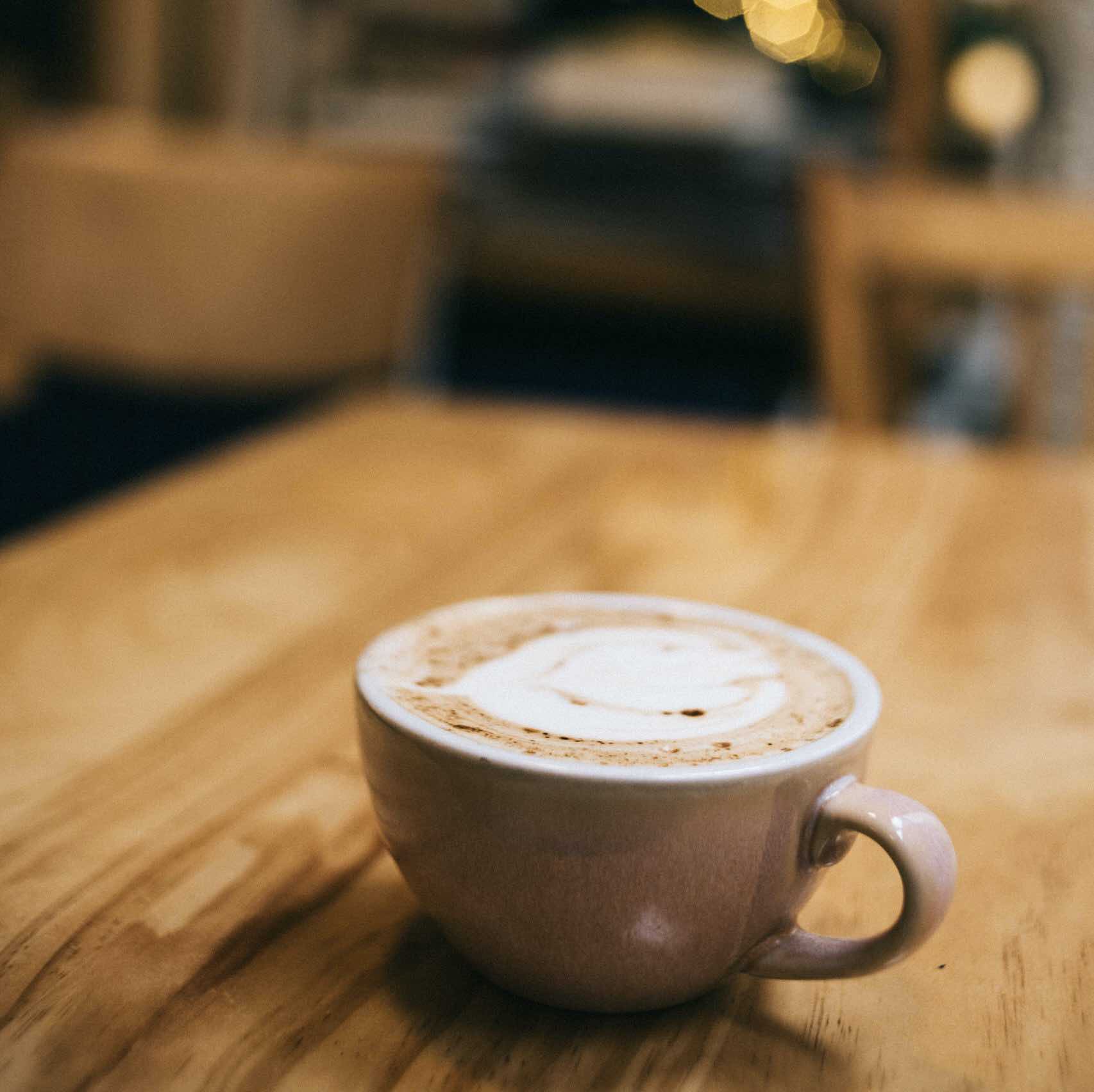 chai latte mousseux et délicieux préparé et servi dans une tasse blanche sur une table en bois