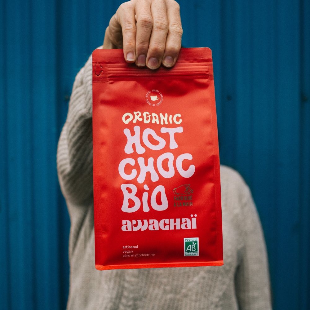 la photo montre le format 1kg de chocolat chaud en poudre de chez awachai, tenu à la main