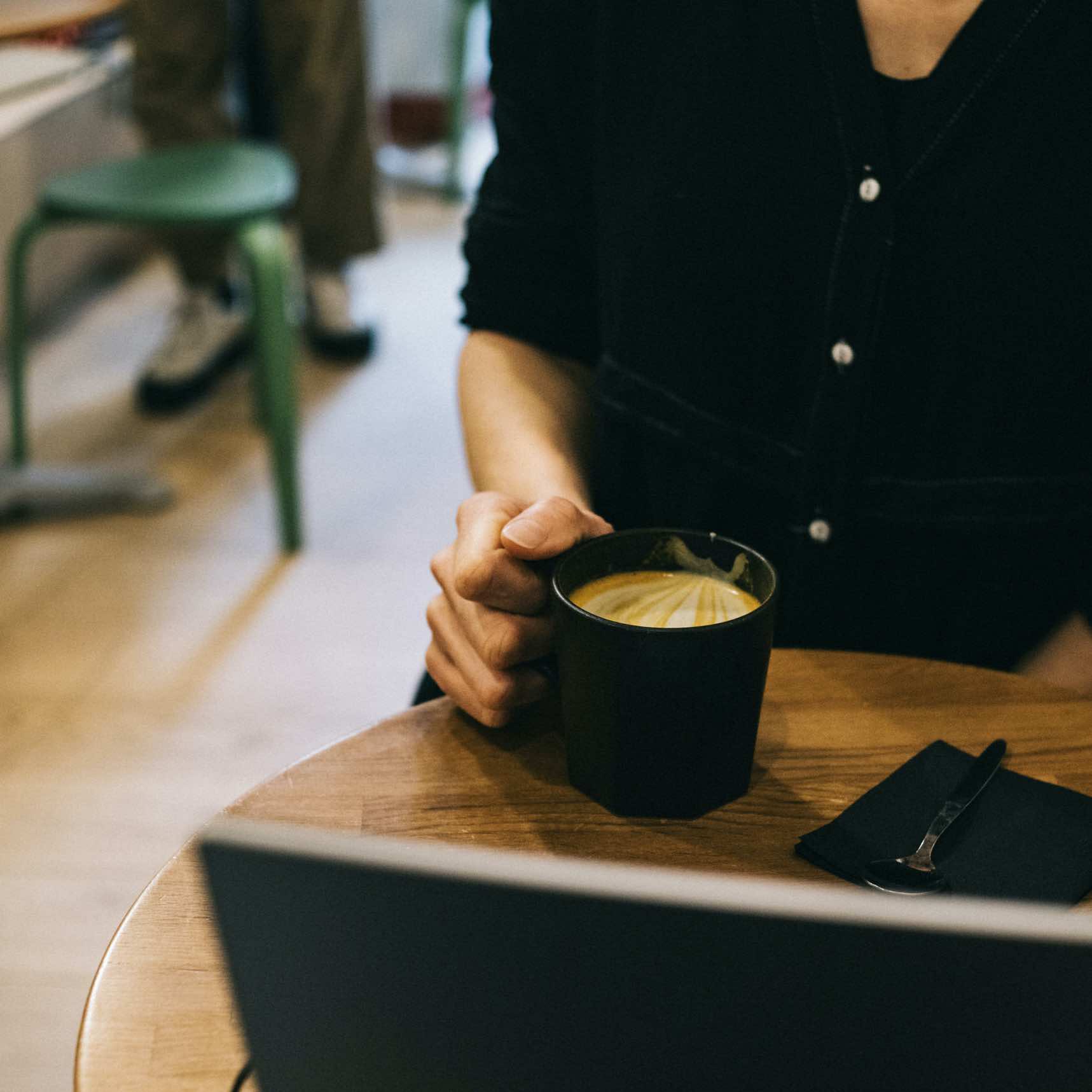 la photo représente une femme dégustant son golen latte de la marque awachai dans un coffee shop