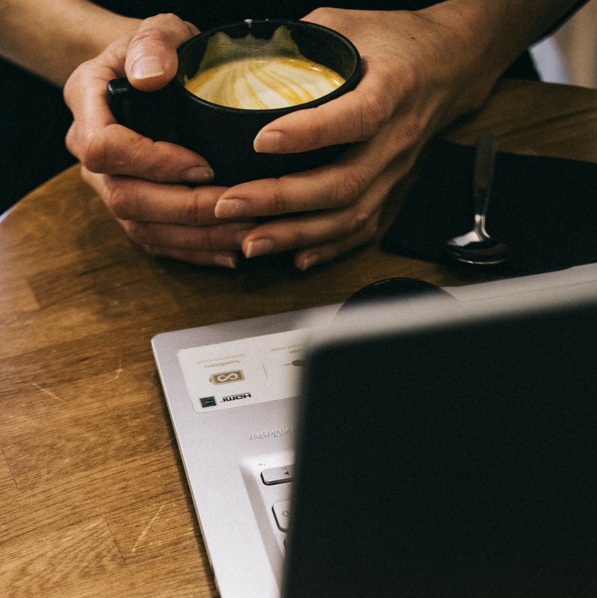 on voit ici des mains tenant une tasse noire dans laquelle est fait le Golden latte bio by awachai pret à etre bu