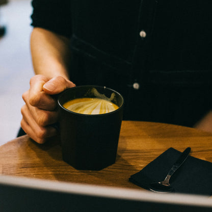zoom sur un golden latte délicieux by awachai servi dans une tasse noire et pret à etre degusté