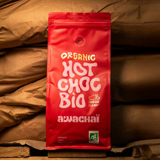 la photo montre le format 1kg de chocolat chaud en poudre de chez awachai, posé sur une palette devant des sacs de marchandises 