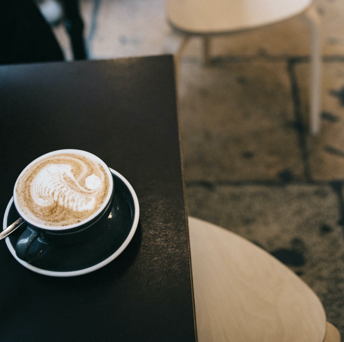 un masala chai est poser sur une table, présenté dans une tasse noir et pret à etre dégusté