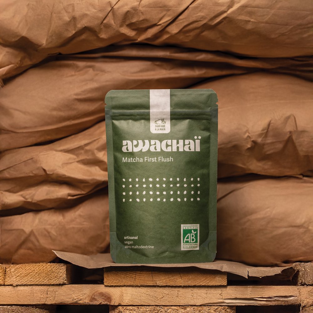 Matcha first flush de chez awachai présenté dans son paquet et posé devant des sacs de marchandises 