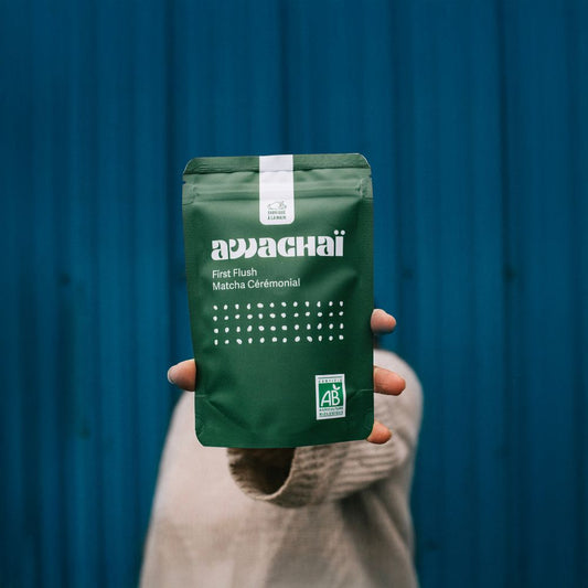 Matcha first flush 100gr de chez awachai présenté dans son paquet et posé tenu à la main