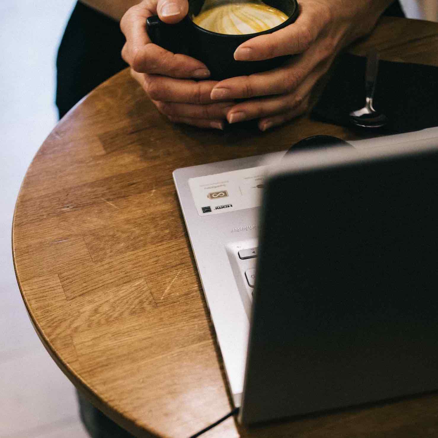 gros plan sur les mains d'une personne tenant son golden latte à la main et le savourant dans un coffee sho